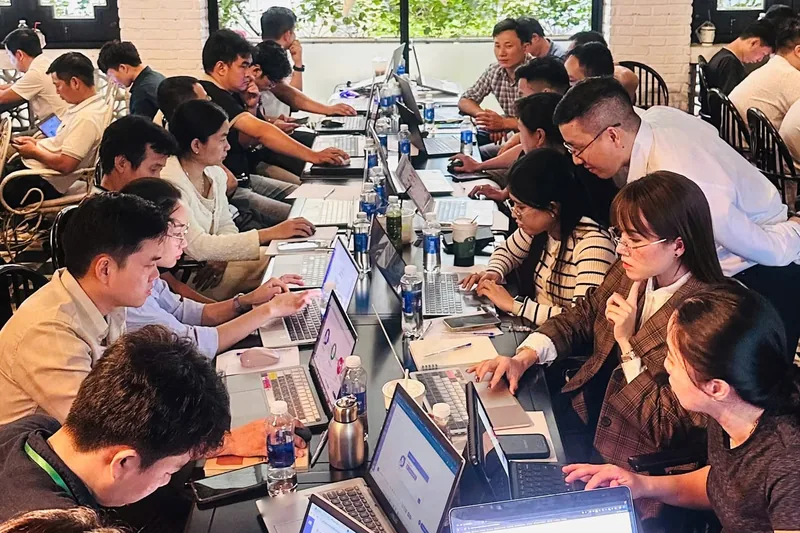 Học viên ngồi quanh bàn dài, thực hành trên laptop trong lớp AI Agent cho doanh nghiệp của The AI Growth