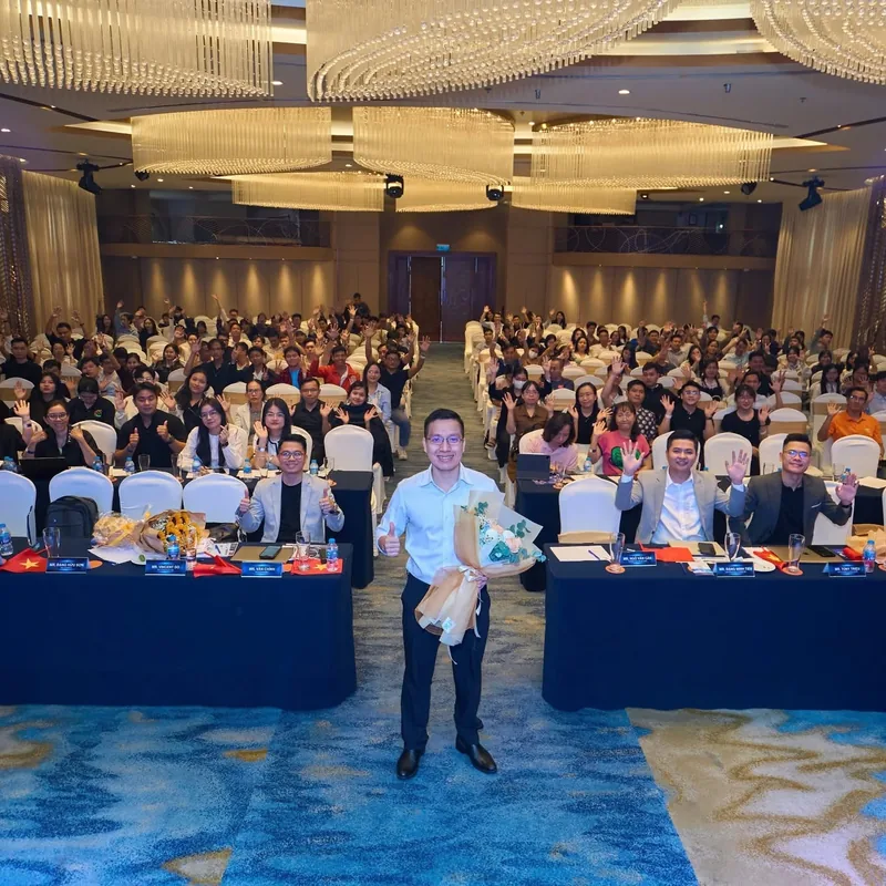 Vincent Do cầm hoa đứng trước khán phòng đang vẫy tay tại sự kiện MKT x Ecom Academy